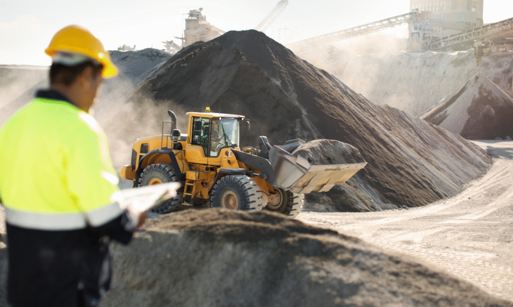 Carregadeira em operação na mineração, com operador monitorando o trabalho em campo.